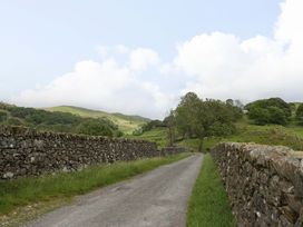 A road alongside stone walls and greenery at Yew Tree Cottage in Torver