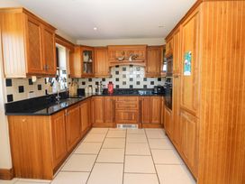 A kitchen with wooden cabinets and black countertops at Stone Cottage in Waterville, County Kerry