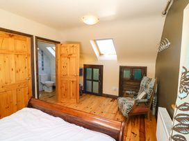 A bedroom with a bed and doors leading to a bathroom at Stone Cottage, Waterville, County Kerry