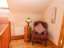 A seating area with a chair and lamp at Stone Cottage in Waterville, County Kerry