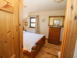 A bedroom with a bed and dresser at Stone Cottage in Waterville, County Kerry