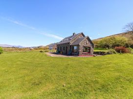 A stone house with garden and mountains in the background at Stone Cottage, Waterville, County Kerry