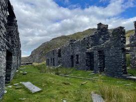Ruins of a slate building surrounded by grass and mountains at Tafarn Trip in Tan Y Bwlch, Maentwrog
