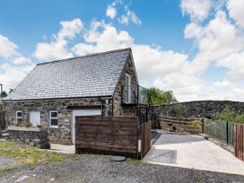 A stone cottage with a slate roof and a driveway next to a stone bridge at Glan Nug Bach in Rhydlydan near Betws-y-Coed