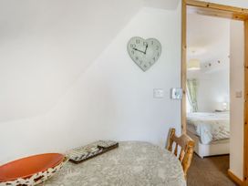 A small dining area with a round table and wooden chair and a heart shaped clock on the wall at Glan Nug Bach in Rhydlydan near Betws-y-Coed