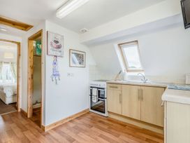 A kitchen with wooden cabinets a stove a sink under a skylight and an open doorway showing a bedroom at Glan Nug Bach in Rhydlydan near Betws-y-Coed