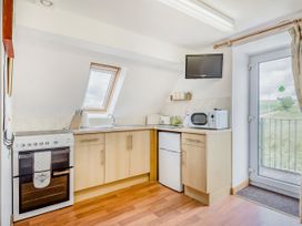 A kitchen with stove oven microwave refrigerator and a door leading outside at Glan Nug Bach in Rhydlydan near Betws-y-Coed