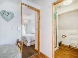 A small dining area with a round table and wooden chair next to doorways leading to a bedroom and bathroom at Glan Nug Bach in Rhydlydan near Betws-y-Coed