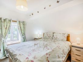 A bedroom with a bed with butterfly patterned bedding and curtains with bedside tables and lamps at Glan Nug Bach in Rhydlydan near Betws-y-Coed