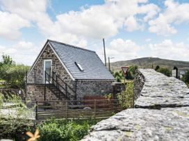 A stone house with a slate roof and external metal stairs next to a stone wall in a rural area at Glan Nug Bach in Rhydlydan near Betws-y-Coed