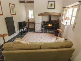 A living room with a wood stove and television at Swallows St Keverne, Lizard Peninsula