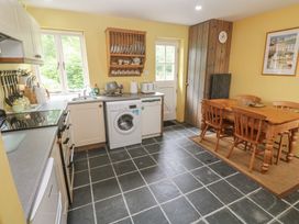 A kitchen with a washing machine and dining table at Swallows St Keverne, Lizard Peninsula