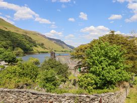 A stone church and green trees by a lake with hills in the background at St.Marys in Tal y Llyn near Dolgellau