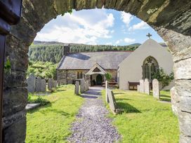 A stone church with a path and gravestones in a grassy churchyard at St.Marys in Tal y Llyn near Dolgellau