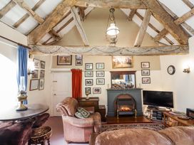 A sitting room with exposed wooden beams a fireplace a television and leather armchairs at St.Marys in Tal y Llyn near Dolgellau