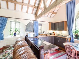 A kitchen with dark cabinets a wooden table a brown leather sofa blue curtains and arched windows at St.Marys in Tal y Llyn near Dolgellau