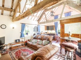 A living room with brown leather sofas and patterned pillows next to a kitchen with wooden chairs and blue curtains at St Marys Tal y Llyn near Dolgellau