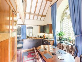 A kitchen with wooden dining table and chairs near a window with blue curtains at St.Marys in Tal y Llyn near Dolgellau