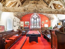 A room with a pool table and wooden benches under wooden beams with stained glass window at St.Marys in Tal y Llyn near Dolgellau
