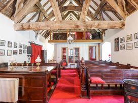 An interior view of a chapel with wooden pews red carpet and exposed wooden ceiling beams at St Marys Tal y Llyn near Dolgellau