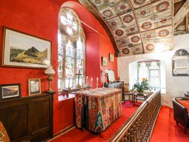 An interior space with red walls stained glass windows a colorful altar table wooden furniture and a patterned ceiling at St.Marys Tal y Llyn near Dolgellau