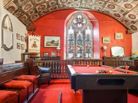 A room with a red pool table stained glass windows wooden benches and framed pictures at St.Marys in Tal y Llyn near Dolgellau