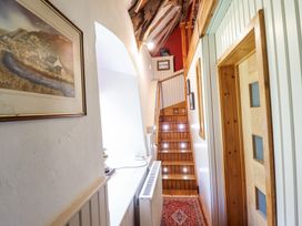 A hallway with wooden stairs and framed pictures on the wall at St Marys Tal y Llyn near Dolgellau