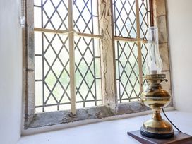 A window with diamond patterned glass panes and a brass oil lamp on the windowsill at St.Marys Tal y Llyn near Dolgellau