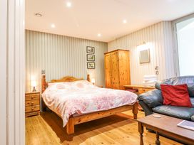 A bedroom with a wooden bed and wardrobe a black sofa with a red pillow and a wooden coffee table at St.Marys Tal y Llyn near Dolgellau