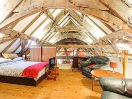 An attic bedroom with a bed small television two black leather chairs and wooden beams at St.Marys Tal y Llyn near Dolgellau