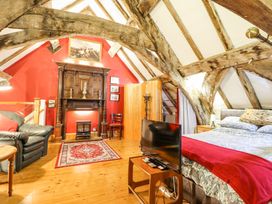 A bedroom with exposed wooden beams a bed a television a fireplace and an armchair at St Marys in Tal y Llyn near Dolgellau