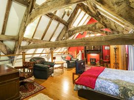 A bedroom with exposed wooden beams two armchairs a desk and a fireplace at St.Marys Tal y Llyn near Dolgellau