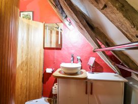 A bathroom with a basin on a wooden countertop and a mirror on a red wall at St.Marys Tal y Llyn near Dolgellau