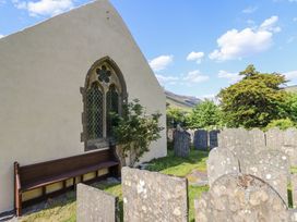 Stone grave markers near a church with a wooden bench and a window with decorative glass at St.Marys in Tal y Llyn near Dolgellau