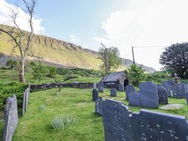 A graveyard with old headstones and a small stone building near a mountain at St.Marys in Tal y Llyn near Dolgellau