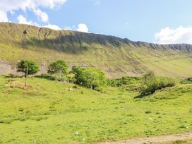 A green grassy field with trees and a large hill in the background at St.Mary's in Tal y Llyn near Dolgellau