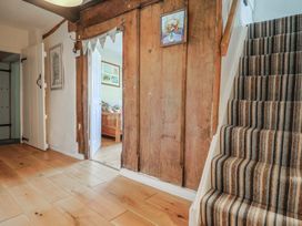 A hallway with a staircase and a wooden door at Church Farmhouse in Winsham