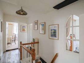 A hallway with a staircase and pictures on the wall at Church Farmhouse in Winsham