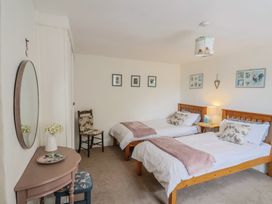 A bedroom with two beds and a chair at Church Farmhouse in Winsham