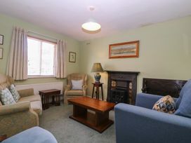 A living room with a sofa, armchair, coffee table, and fireplace at The Lock House in Gloucester