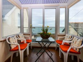 A conservatory with chairs and a table overlooking the sea at Min Y Traeth in Bull Bay