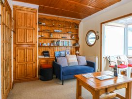 A living room with a sofa and bookshelf at Min Y Traeth Bull Bay