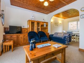 A living room with a television, sofa, and coffee table at Min Y Traeth in Bull Bay