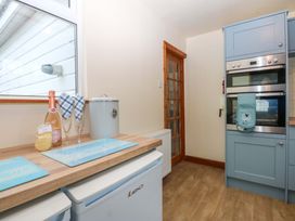 A kitchen with a window, glassware, and built-in oven at Min Y Traeth in Bull Bay
