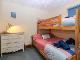 A bedroom with a bunk bed and dresser at Min Y Traeth in Bull Bay