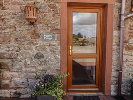 An entryway with a wooden door and flower pot at Piggery Cottage Wigton