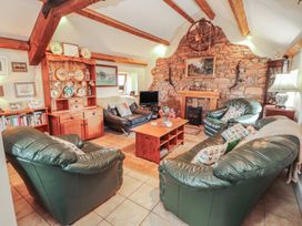 A living room with green sofas and a fireplace at Piggery Cottage in Wigton