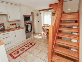 A kitchen with cabinets and dining area at Piggery Cottage in Wigton