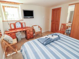 A bedroom with a bed and a dressing table at Piggery Cottage in Wigton