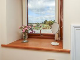 A window with a flower vase and a mirror at Piggery Cottage in Wigton